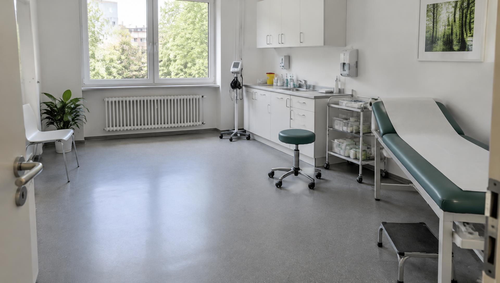 Behandlungsraum einer Arztpraxis mit Untersuchungsliege und Schränken